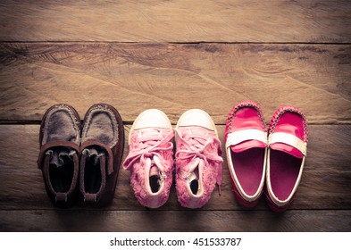 3 Pair Of Baby Shoes Lined Up On Wood Background 