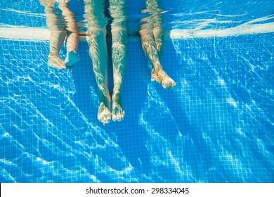 3 Pairs Of Feet Under Water In A Swimming Pool