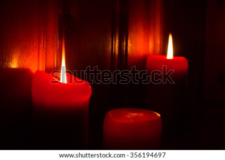 3 red burning candles lighting the darkness.