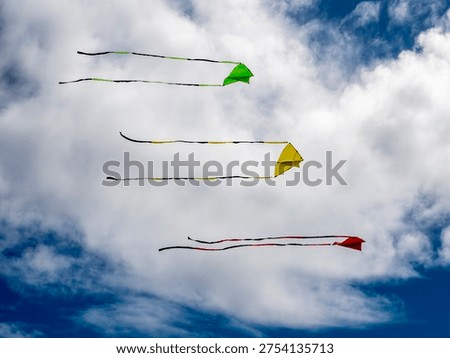 3 simple triangular kites flying in formation in preparation for the annual kite festival at Ōtaki Beach in New Zealand