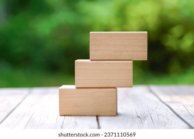 3 stacking rectangle empty wooden blocks on table with green natural blur background for own customer text or letters. Idea of environment, energy or business concept. Front view, banner copy space.