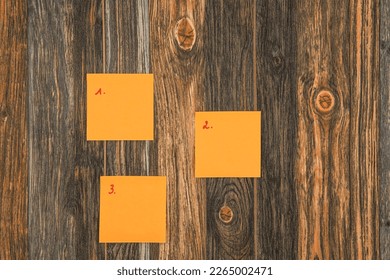 3 Sticky notes on a brown wooden background numbered from 1 to 3