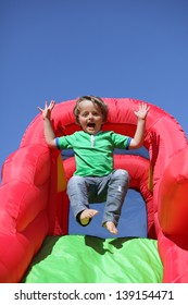 3 year old boy jumping down the slide on an inflatable bouncy castle - Shutterstock ID 139154471