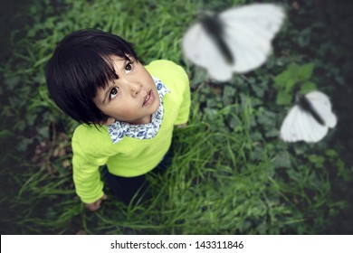 3 year old toddler looking up at white butterflies flying
