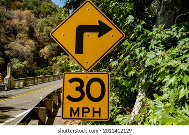 30 mph turn sign on a bridge. Sunny day. Forest scene