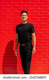 30 Year Old Latin Man In Black Clothes And Glasses On Red Brick Background