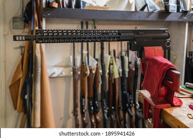 300 Blackout AR Rifle Upper Receiver In A Vise On A Working Table At A Gun Shop In California, Blurred Rifles In The Background