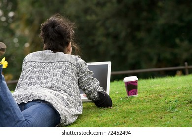 30-35 Years Old Beautiful Woman Lying Grass Working On Laptop Computer In Natural In  Park