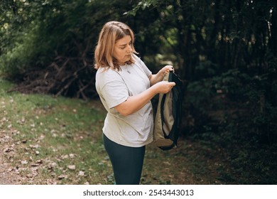 30s young woman preparing her chair amidst the beauty of the nature. Camping, tourism and travel concept. A happy blonde woman explores a forest - Powered by Shutterstock