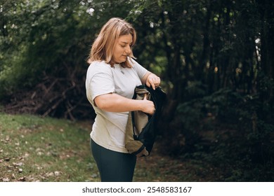 30s young woman preparing her chair amidst the beauty of the nature. Camping, tourism and travel concept. A happy blonde woman explores a forest - Powered by Shutterstock