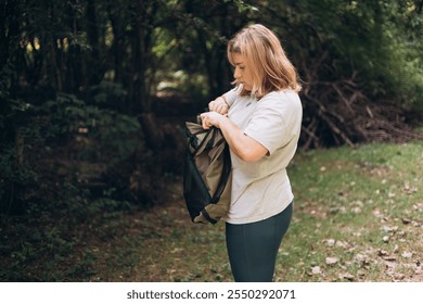 30s young woman preparing her chair amidst the beauty of the nature. Camping, tourism and travel concept. A happy blonde woman explores a forest - Powered by Shutterstock