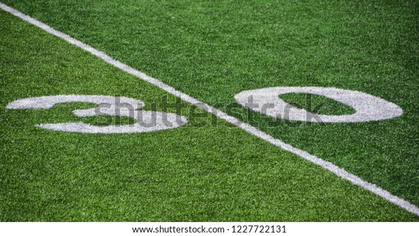 The 30-yard-line of an american football field with\
artificial turf