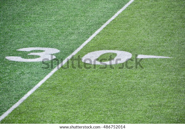 The 30-yard-line of an american football field with\
artificial turf