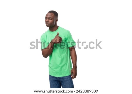 A 30-year-old African man dressed in a light green t-shirt points his hand at an advertisement [[stock_photo]] © 