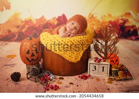 31 october, Haloween day, Baby lying in a wood basket to celebrate the holidays including pumpkin head, dried tree, maple, cherry, gold money with orange and yellow maple background. 