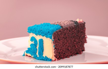 31st birthday party celebration, Chocolate icing cake slice on a plate, number 31 in blue icing decoration on the side. Delicious beautiful mouthwatering cake slice close up.