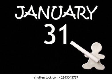 31st day of January. A small white plasticine man writing the date 31 January on a black board. Business concept. Education concept. Winter month, day of the year concept.