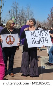 3-24-2019 Tulsa USA Two Older Women With Protest Signs - One A Peace Symbol And The Other Saying Never Again At Rally In Park