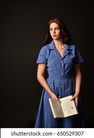 3/4 portrait of a brunette girl wearing a vintage blue dress again a black studio backdrop.