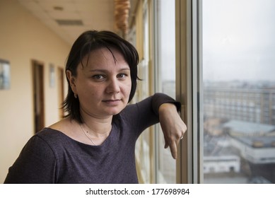 35 Year Old Woman Stands In Front Of The Window. Real People Series