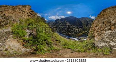 360-degree equirectangular panorama of a rugged mountain gorge in Kyrgyzstan. Steep cliffs and lush vegetation flank a turbulent river, creating a stunning natural landscape.