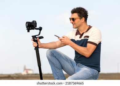 3-axis outdoor vlogger gimbal smartphone controlled digital camera stabilizer gimbal. Cameraman handle with mobile phone. Phone controlled gimbal cameraman concept in hand.  mirrorless Motorize gimbal
