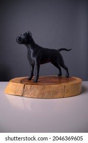 
3D All-black Guard Dog Figure Made In Plastic On A Wooden Base. Studio Photo Of Breed Dog Model Mockup.