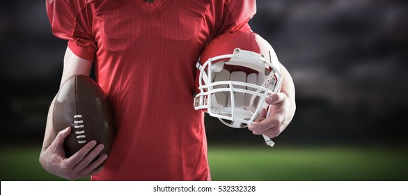 3D American football player holding a helmet and ball against gloomy sky - Powered by Shutterstock
