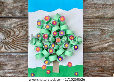 3D applique of colored paper, volume, spring tree with flowers, on a wooden background, handmade.