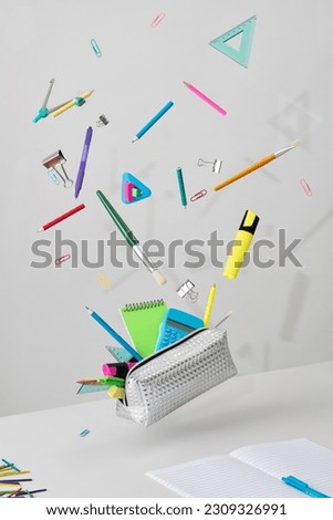 3D Fly stationery set. Levitation of notepad, pencils, pen, sticker and binder clips. Isolated on a grey backdrop.