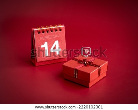 3d love like heart icons floating on small red present gift box with February ,14 Valentine's day on desk calendar cover on red background. Special gift for Valentine's Day, minimal style.