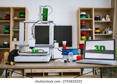 A 3D printer is actively creating green letters on its build plate, surrounded by spools of filament and a laptop displaying the 3D logo