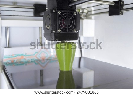 3D printer close up. A working 3D printer in process of printing object from molten plastic. 3D printer creating model by flowing liquid plastic from an extruder of printer. 3D printing technology