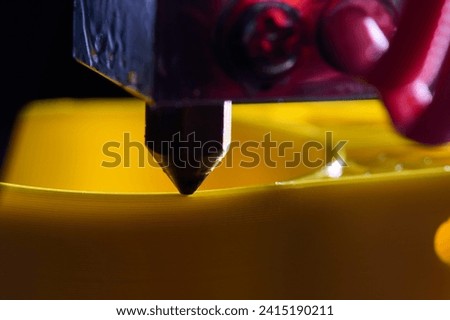 3D printer printing a part made of yellow plastic, close-up view