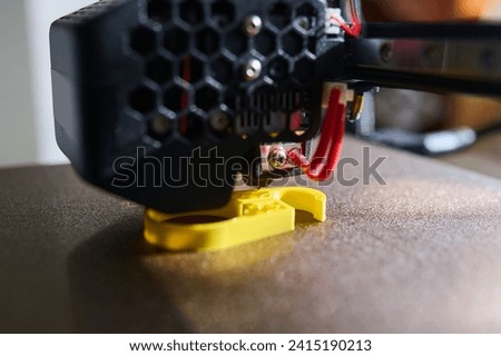 3D printer printing a part made of yellow plastic, close-up view