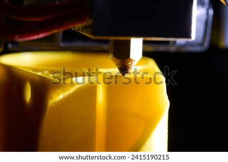 3D printer printing a part made of yellow plastic, close-up view
