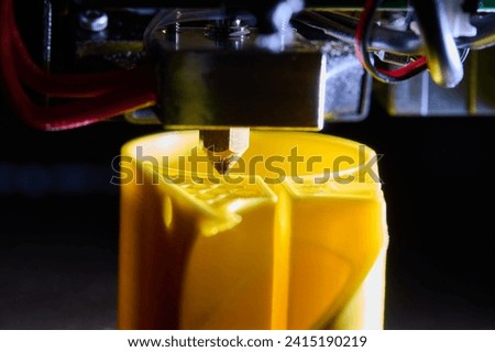 3D printer printing a part made of yellow plastic, close-up view