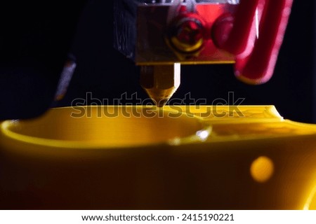 3D printer printing a part made of yellow plastic, close-up view