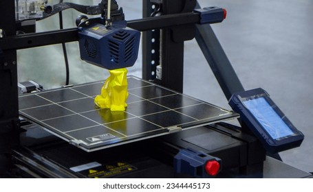 3D printer printing prototype of toy from molten plastic. Process of creating prototype model of toy on 3D printer from yellow melted plastic close-up. Additive new printer technology. Modern printing