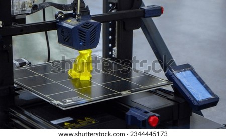 3D printer printing prototype of toy from molten plastic. Process of creating prototype model of toy on 3D printer from yellow melted plastic close-up. Additive new printer technology. Modern printing