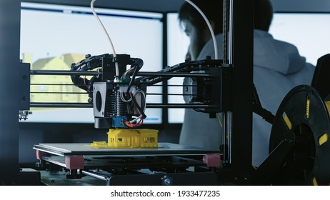 3d Printer printing yellow small house with engineer constructor in background at pc model