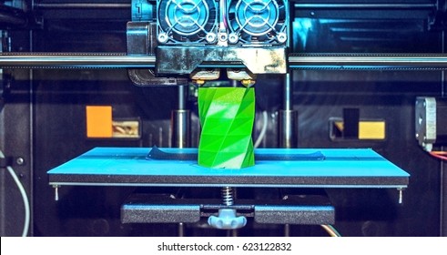 3D printer works and creates an object from the hot molten plastic close-up. Automatic three dimensional 3d printer performs plastic green colors modeling in laboratory.