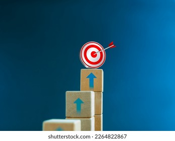 3d target icon on the top of wooden cube blocks, bar graph chart steps with up arrows on blue background. Business growth process, investment, income, trends, inflation, economic improvement concepts. - Powered by Shutterstock