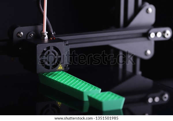 3D-printer manufacturing exclamation mark from\
green plastic - close up view on print head, print bed and object\
in dark surrounding - background blanked out blurry - technology\
opportunity concept