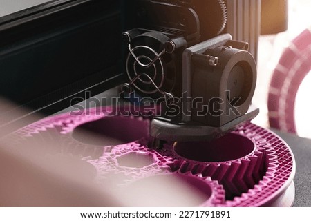 3D-printing of a planetary gear part from pink plastic filament in inspiring surrounding. selective focus. Visible infill structure and layers. View on print head. Modern production concept