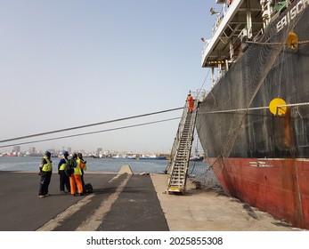 3May2018 At Dakar, Senegal. A Group Of Stevedore Is Waiting To Board A Cargo Ship Or Bulk Carrier While A Ship Crew Is Walking On A Gangway Ladder.