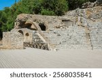 The 3rd century Roman Amphitheatre in Butrint Archaeological Park, within Butrint National Park, southern Albania. A UNESCO World Heritage Site. On the left of the Cavea seating area is a Parodos. 