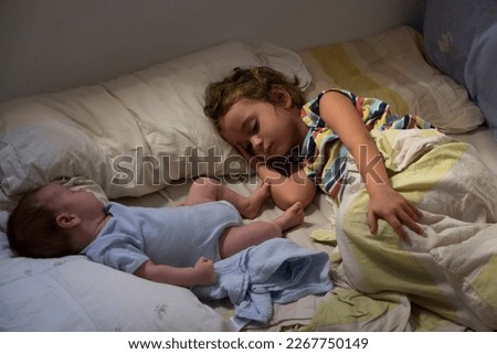 Similar – Little girl embracing doll lying over the bed