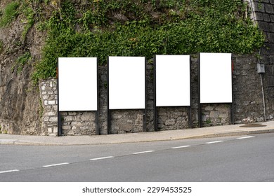 4 billboards on the street on the green overgrown wall. - Shutterstock ID 2299453525