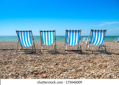 4 blue deck chairs on a pebble beach